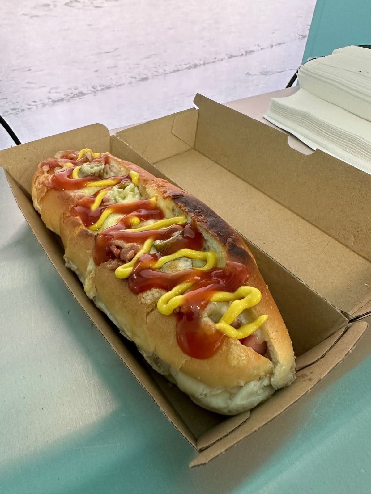 A loaded hot dog in a takeaway box
